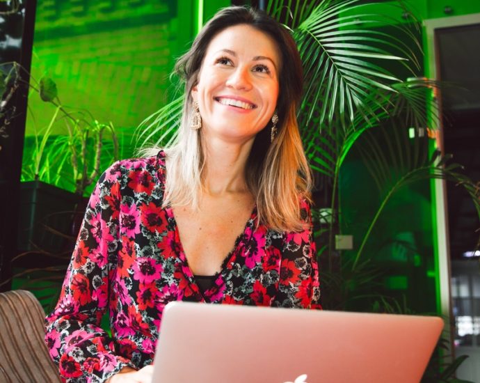 Woman in Red and Black Floral Dress Using Macbook