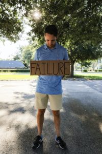 man in blue and white crew neck t-shirt holding brown wooden signage